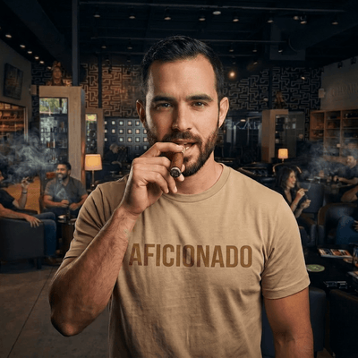Sand T-Shirt with Sand Aficionado Logo on White Male Smoking a Cigar in Aficionados Lounge